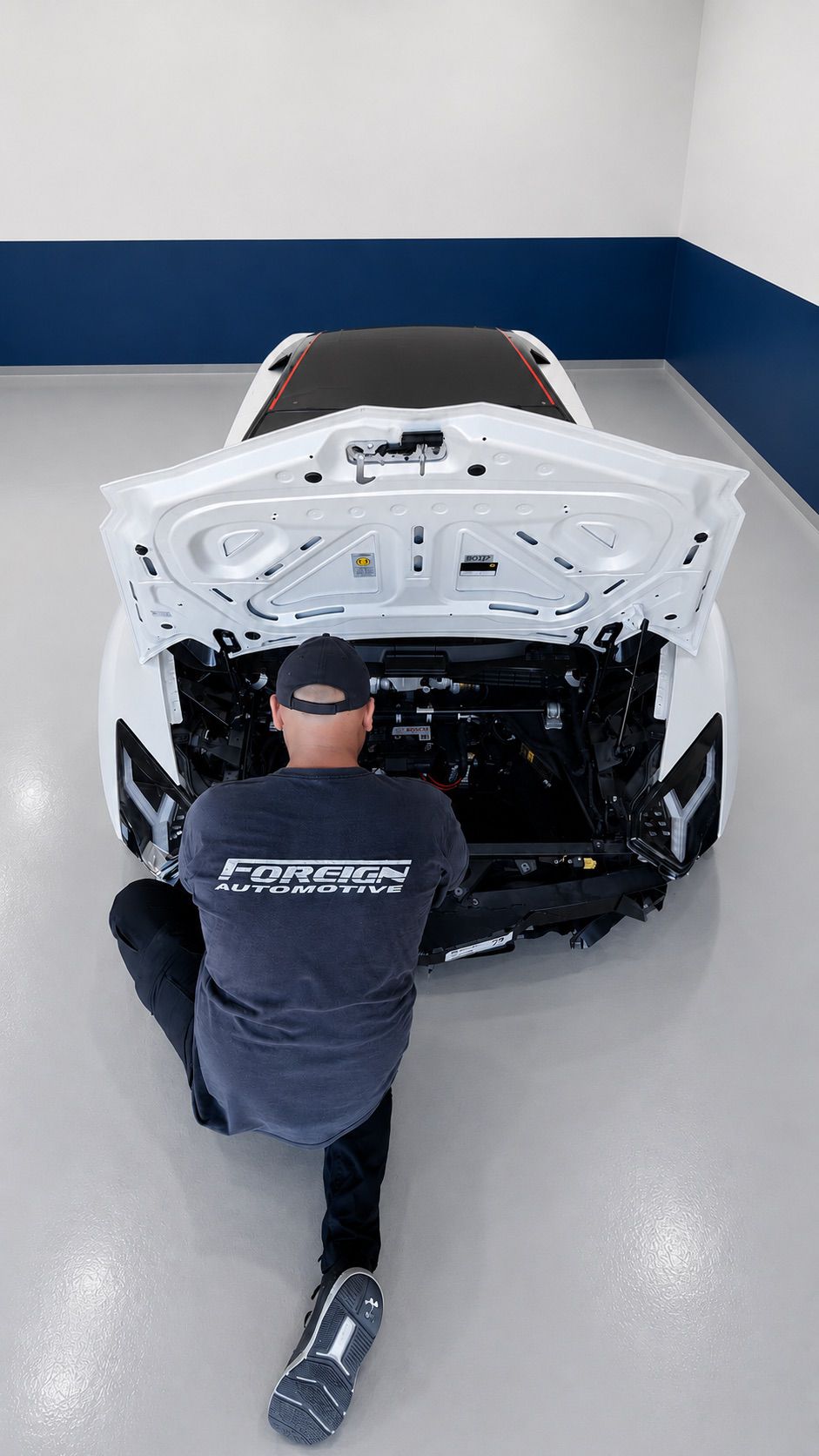 Foreign Automotive technician working at the open front compartment of a white sports car