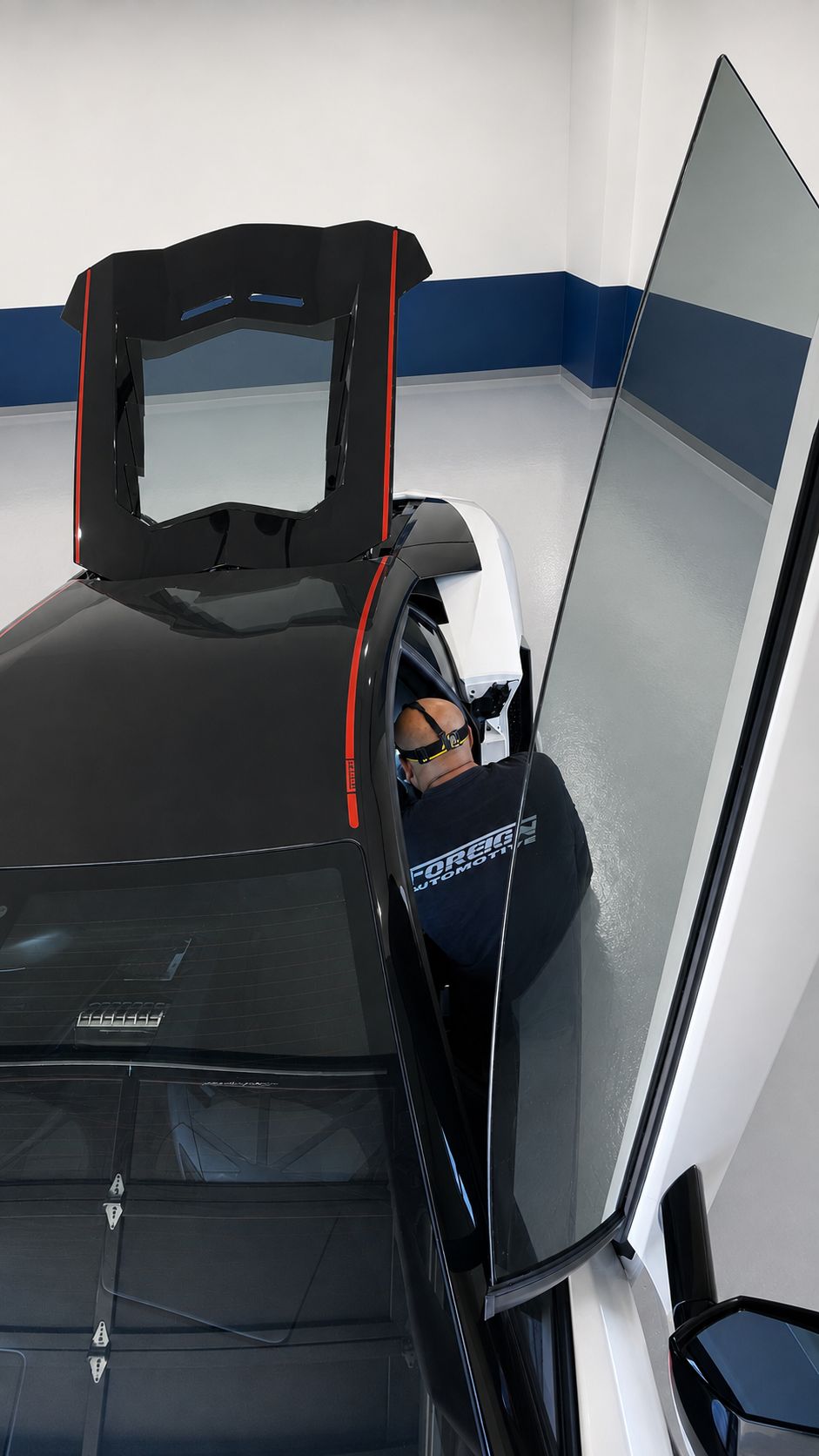 Foreign Automotive technician working beside a sports car with its body panels open