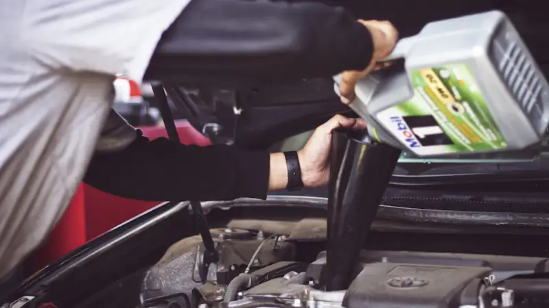 Technician topping up engine oil — factory scheduled maintenance