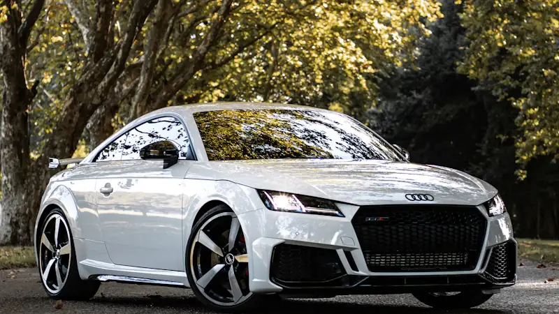 White Audi TT parked beside trees